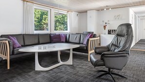 A modern living room with a sectional sofa, a round coffee table, and a leather armchair.