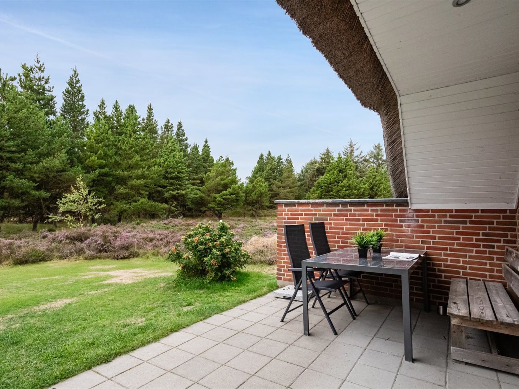 Eine Terrassengruppe im Freien mit Backsteinmauer, Tisch und Stühlen.