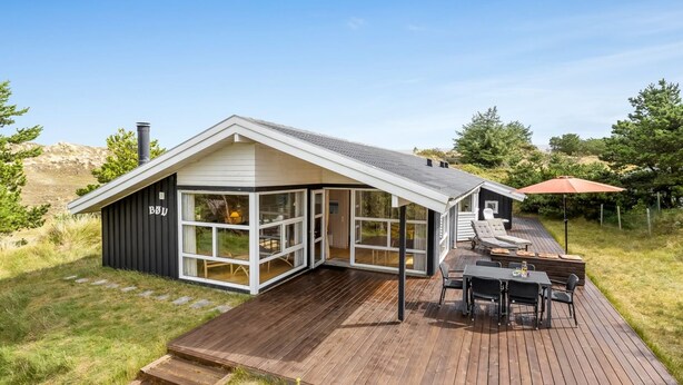 Een modern huis met een ruim terras, een kamer met glazen wanden en een patio met tuinmeubilair.