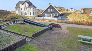 A coastal area with a large building, a smaller house, and a playground with a slide. - "Britt" - 100m from the sea by Interhome (Fanø)