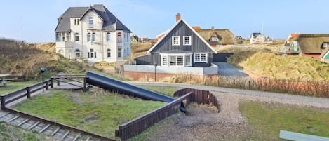 A coastal area with a large building, a smaller house, and a playground with a slide.