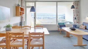 A modern living room with a dining area, large windows, and a view of a building outside. - "Britt" - 100m from the sea by Interhome (Fanø)