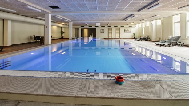 A large indoor swimming pool with a tiled ceiling, lounge chairs, and a small poolside area. - "Britt" - 100m from the sea by Interhome (Fanø)