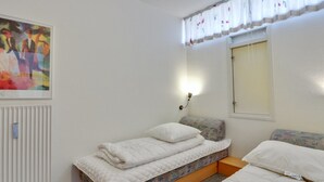 A bedroom with two beds, a radiator, a painting, and a window with curtains. - "Britt" - 100m from the sea by Interhome (Fanø)
