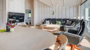 Un salon moderne avec un grand canapé en cuir noir, une table à manger en bois et un téléviseur.