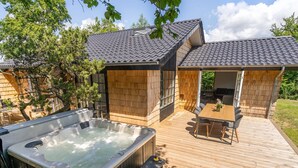 Une terrasse en bois avec un jacuzzi, une table et des chaises, et un espace patio couvert.