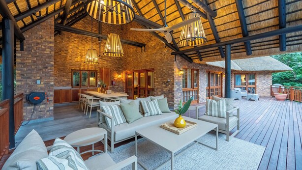 An outdoor patio with a brick wall, wooden deck, and a dining area with a table and chairs.