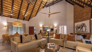 A spacious living area with a high ceiling, a large window, and a dining area.