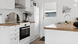 A modern kitchen with white cabinetry, a built-in oven, a coffee maker, and a sink with a window above it. - "Silvana" - 750m from the sea by Interhome (Væggerløse)