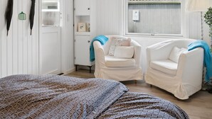 A cozy room with a bed, two white armchairs, a small cabinet, and a window with a view of a building. - "Silvana" - 750m from the sea by Interhome (Væggerløse)