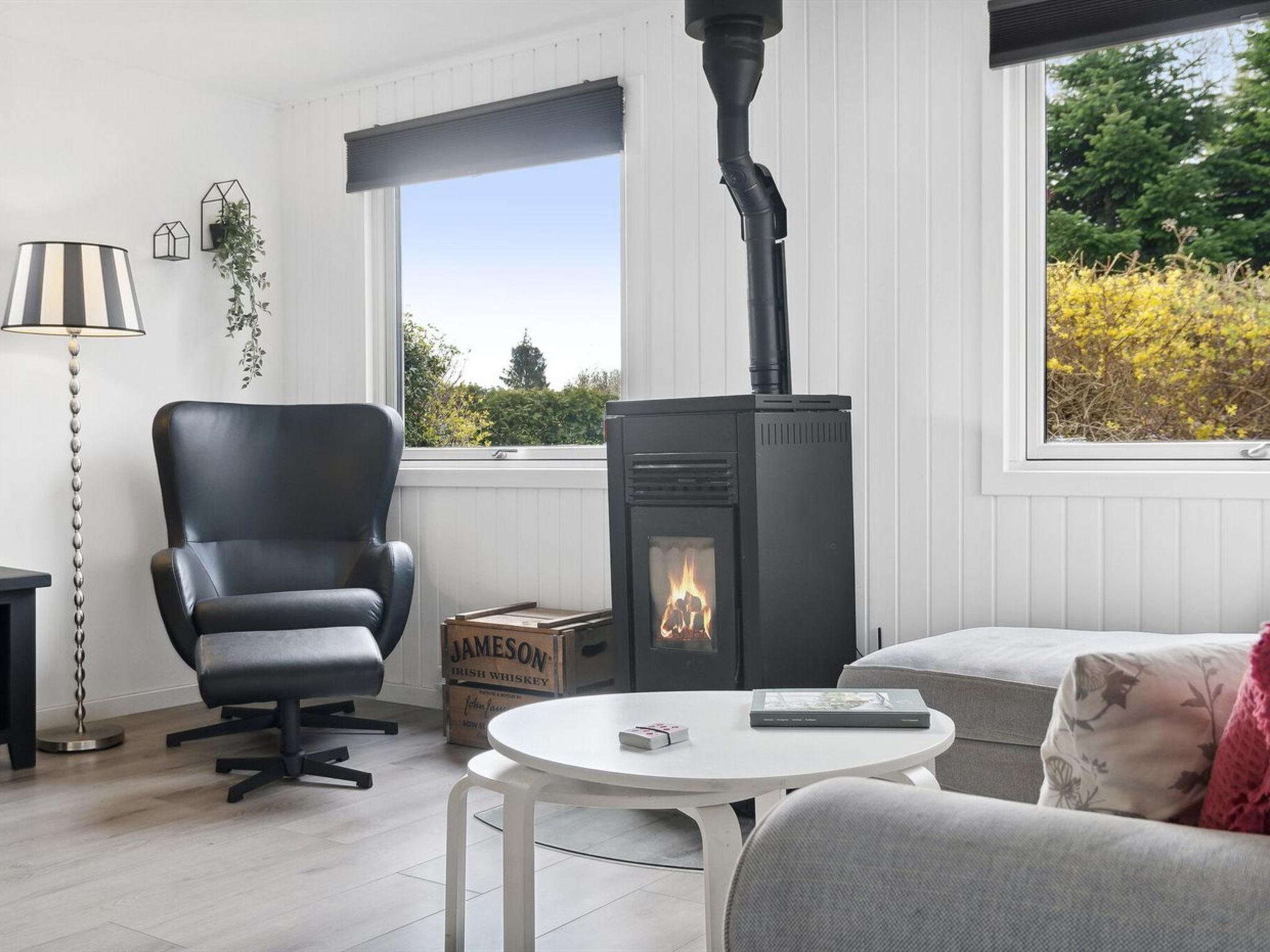 Une pièce chaleureuse avec un fauteuil en cuir noir, une table blanche et un poêle à bois.