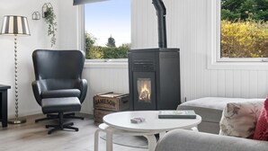A cozy room with a black leather chair, a white table, and a wood-burning stove. - "Silvana" - 750m from the sea by Interhome (Væggerløse)