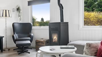 Une pièce chaleureuse avec un fauteuil en cuir noir, une table blanche et un poêle à bois.