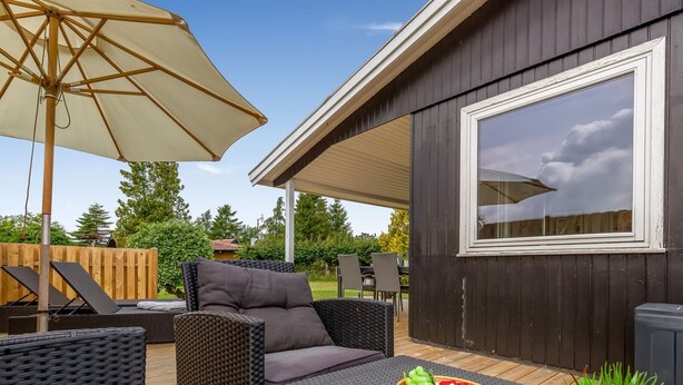 A covered patio area with wicker furniture, a table with a fruit basket, and a large umbrella. - "Silvana" - 750m from the sea by Interhome (Væggerløse)