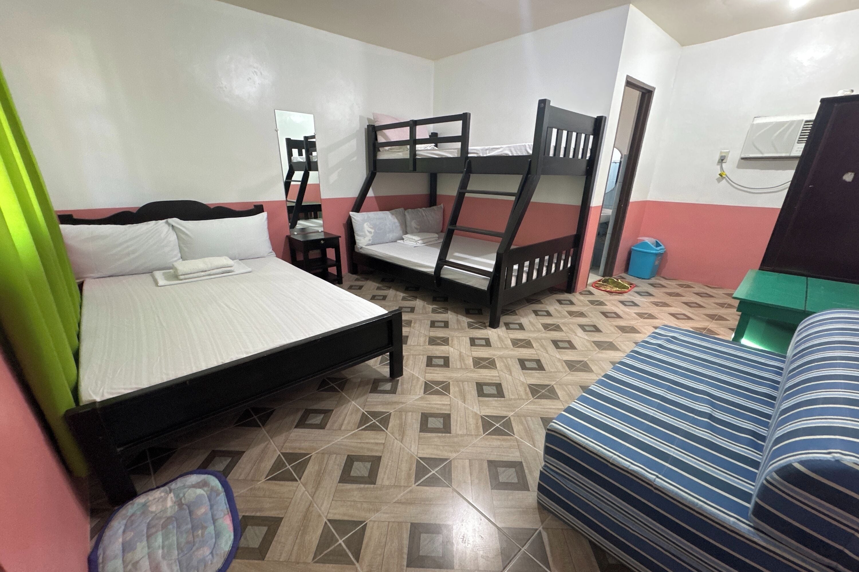 A room with bunk beds, a single bed, a striped sofa, and a small table.