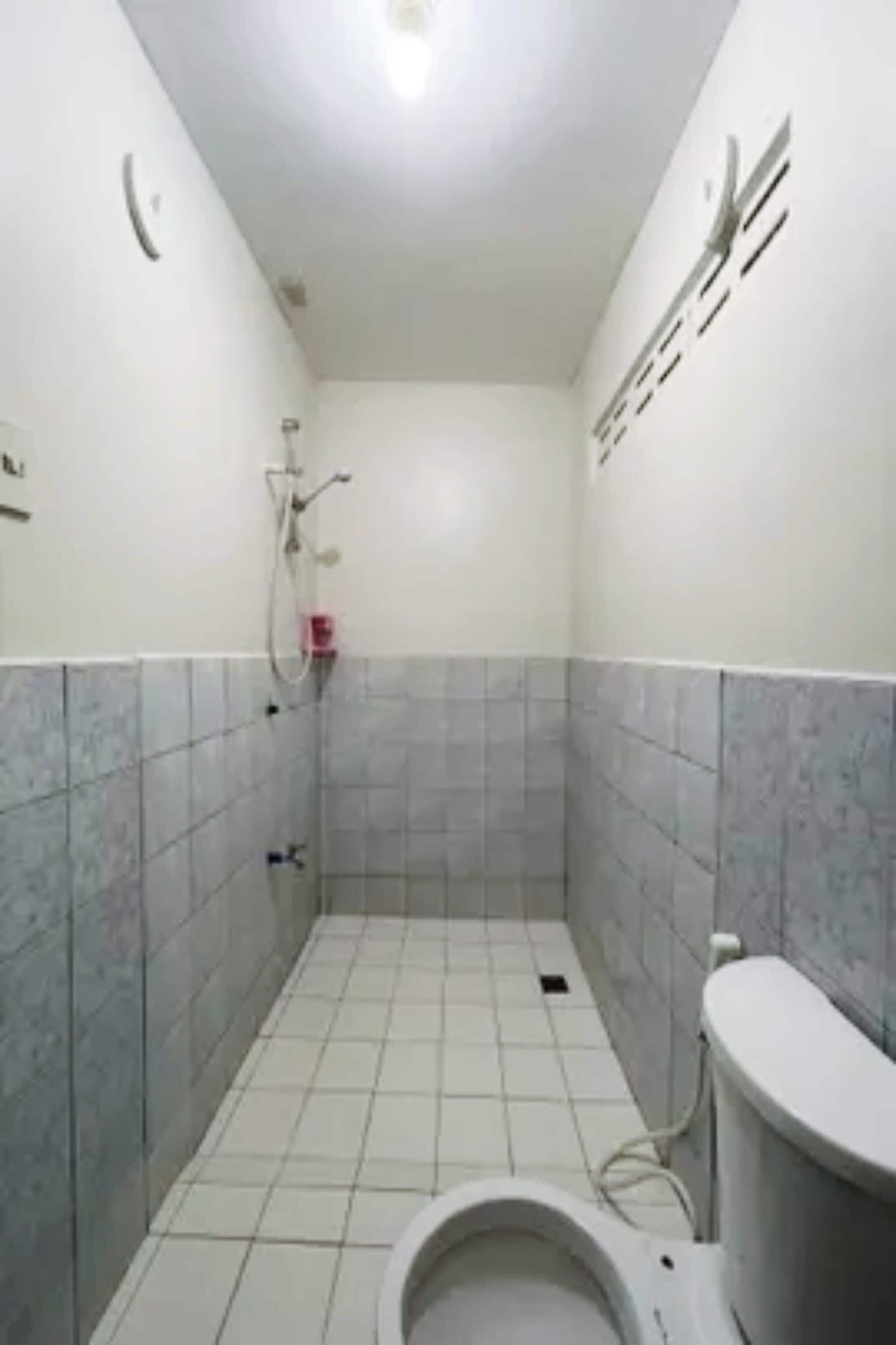 Un baño pequeño con inodoro, ducha y paredes de azulejos.