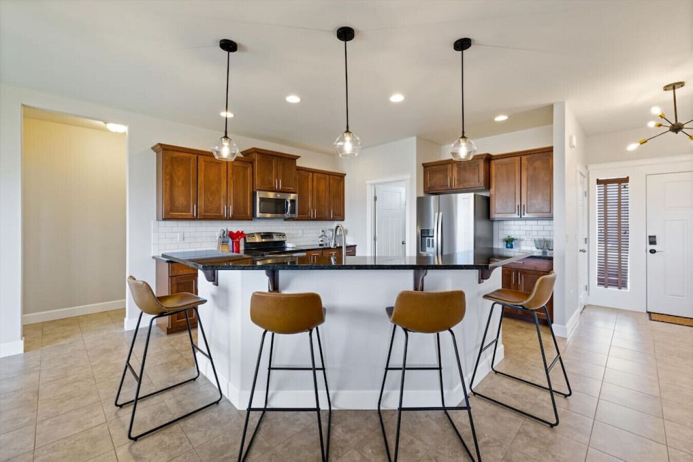 A modern kitchen with wooden cabinets, stainless steel appliances, and a central island with bar stools.