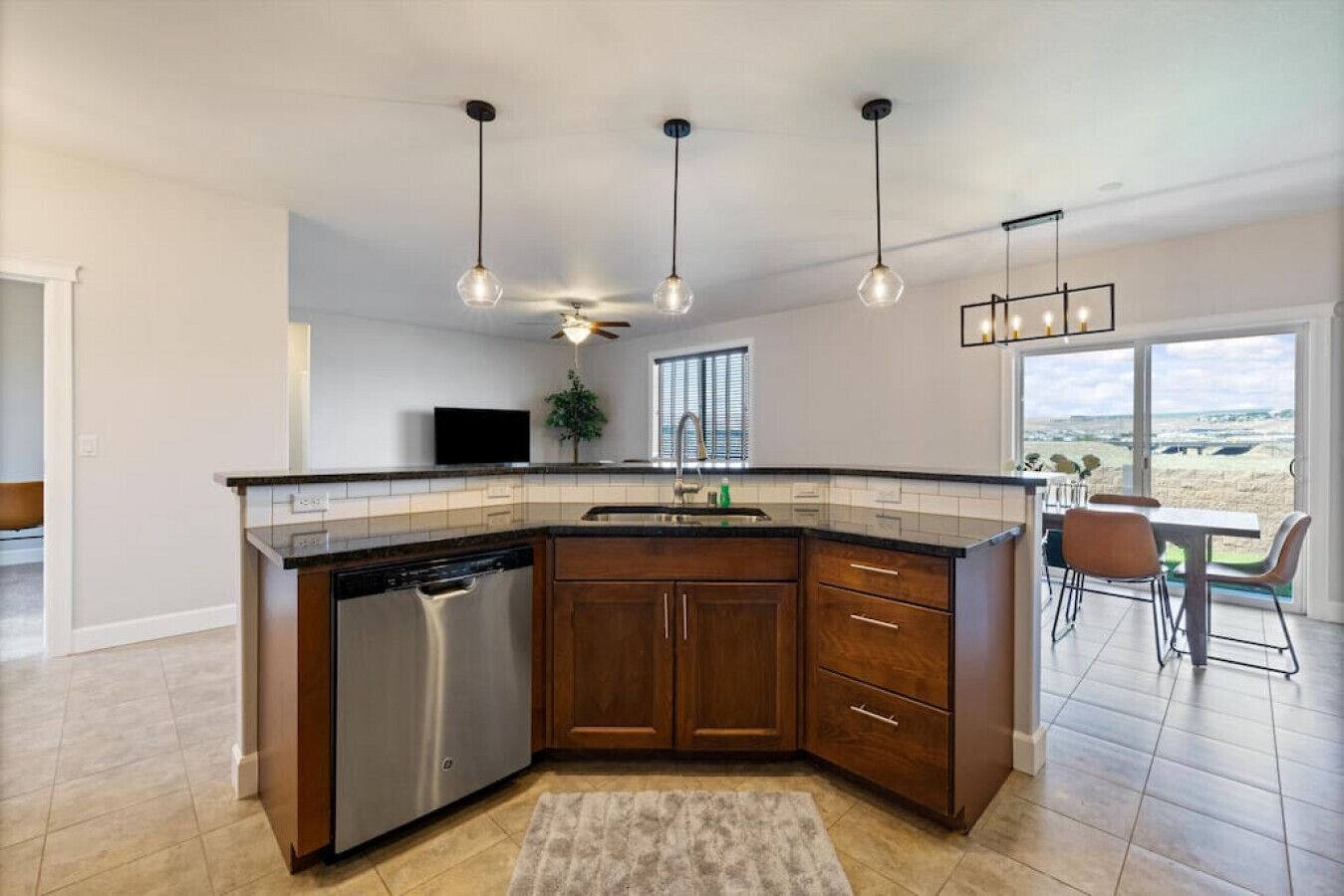 A modern kitchen with dark wood cabinets, a dishwasher, and pendant lighting.
