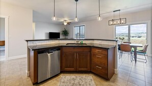 A modern kitchen with dark wood cabinets, a dishwasher, and pendant lighting. - Conveniently located Clean Rambler. (Kennewick)