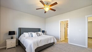 A bedroom with a bed, nightstands, a ceiling fan, and a door leading to another room. - Conveniently located Clean Rambler. (Kennewick)