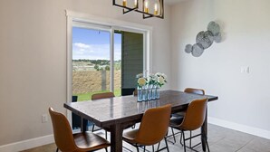 A dining area with a large table, four chairs, a chandelier, and a view through a sliding door to an outdoor area. - Conveniently located Clean Rambler. (Kennewick)