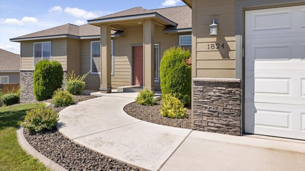 A two-story house with a stone facade, a red door, and a garage number 1824. - Conveniently located Clean Rambler. (Kennewick)