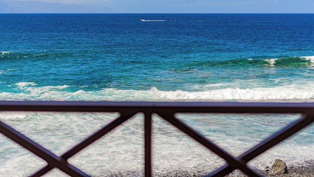 A view of the ocean from a balcony with a metal railing.