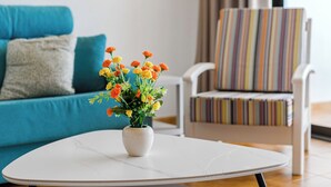A living room with a white round table, a blue sofa, and a striped armchair.