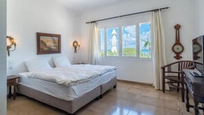 A bedroom with a bed, a desk, a chair, a clock, and a painting on the wall. - Las Gaviotas Style & Charm by Interhome (Ses Salines)