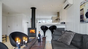 Una sala de estar moderna con una estufa de leña, un sofá y una mesa de comedor con velas.