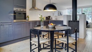 Una cocina moderna con armarios oscuros, una mesa redonda y cuatro sillas.