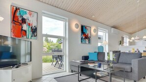 Moderni olohuone, jossa on litteänäyttöinen televisio, sohva, sohvapöytä ja taideteoksia seinillä.