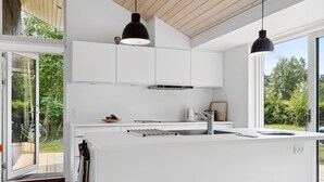 A modern kitchen with white cabinetry, a large island, and pendant lighting. - "Elin" - 200m from the sea by Interhome (Idestrup)