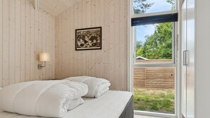 A bedroom with a bed, a framed map on the wall, and a sliding glass door to the outside. - "Elin" - 200m from the sea by Interhome (Idestrup)
