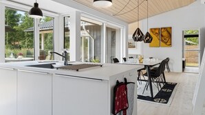 A modern kitchen with a large island, pendant lighting, and a dining area with a view of the outdoors. - "Elin" - 200m from the sea by Interhome (Idestrup)