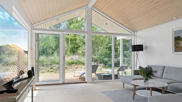 A spacious living area with a large glass door leading to an outdoor deck, a grey sofa, a coffee table, and a flat-screen TV. - "Elin" - 200m from the sea by Interhome (Idestrup)