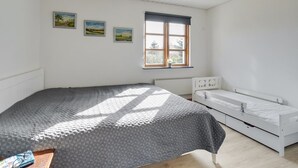 A bedroom with a large bed, a smaller bed, a window with a view, and three landscape paintings on the wall. - "Annegret" - 250m from the sea by Interhome (Idestrup)