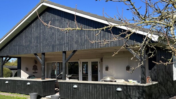 A modern building with a dark exterior, a covered patio area, and a small outdoor seating space. - "Annegret" - 250m from the sea by Interhome (Idestrup)
