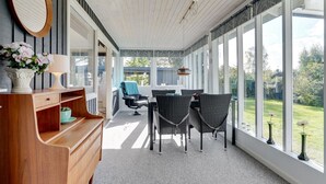 A sunlit room with a wooden desk, two wicker chairs, and a view of a garden through large windows. - "Ilene" - 1km from the sea by Interhome (Bogø By)