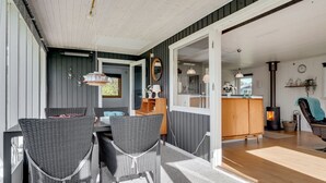 A cozy dining area with wicker chairs and a table, a kitchen with wooden cabinets, and a visible fireplace. - "Ilene" - 1km from the sea by Interhome (Bogø By)