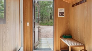 A wooden cabin interior with a door leading to an outdoor area, a bench, and a small table. - "Elsia" - 280m from the sea by Interhome (Nexø)
