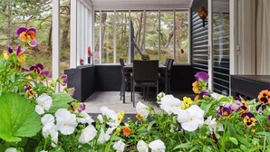 A covered outdoor area with a table and chairs, surrounded by a variety of flowers. - "Elsia" - 280m from the sea by Interhome (Nexø)