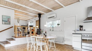 Une cuisine moderne avec des meubles blancs, un four encastré et un coin repas comprenant une table ronde et des chaises blanches.