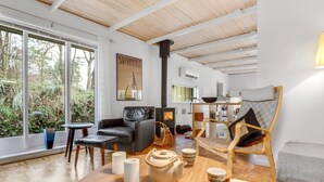 Un salon chaleureux avec une cheminée, un canapé, une table à manger et une vue sur l’extérieur.