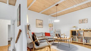 Un salon moderne comprenant un canapé, un fauteuil, une table basse et une bibliothèque.