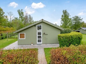 Een groen laag gebouw met een schuin dak, een voordeur en een klein raam.