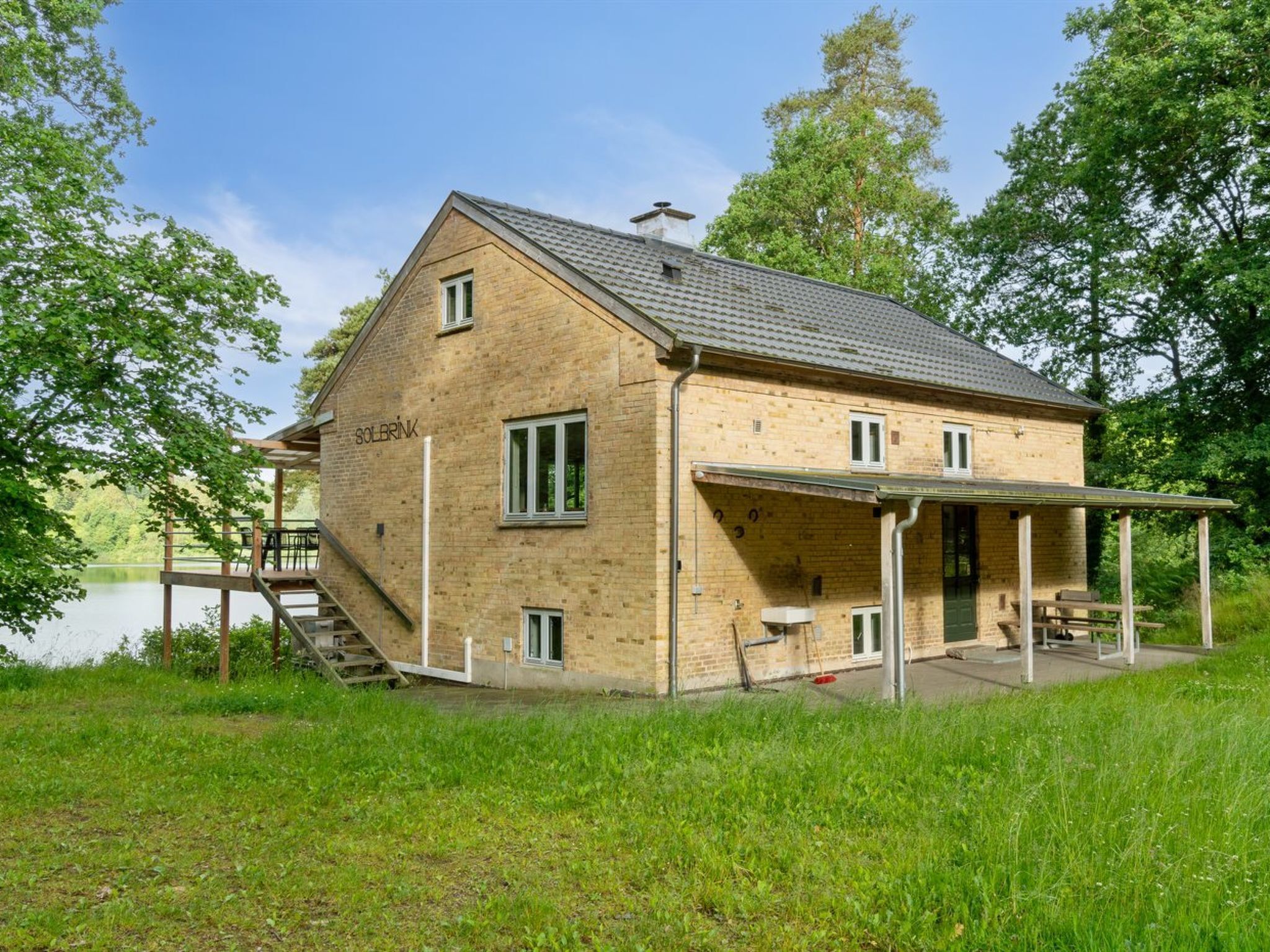 A two-story building with a covered patio area, a staircase leading to a dock, and a sign reading "SOLBRINK".