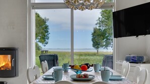 A dining area with a view of the sea, a fireplace, and a television.