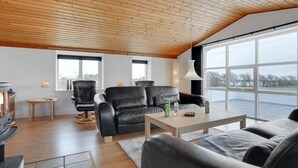 A modern living room with a wooden ceiling, two black leather sofas, a wooden coffee table, and a fireplace. - "Imilie" - 250m to the fjord by Interhome (Redsted Mors)