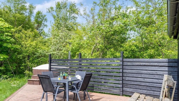 An outdoor patio with a wooden deck, a table with chairs, and a wooden fence.